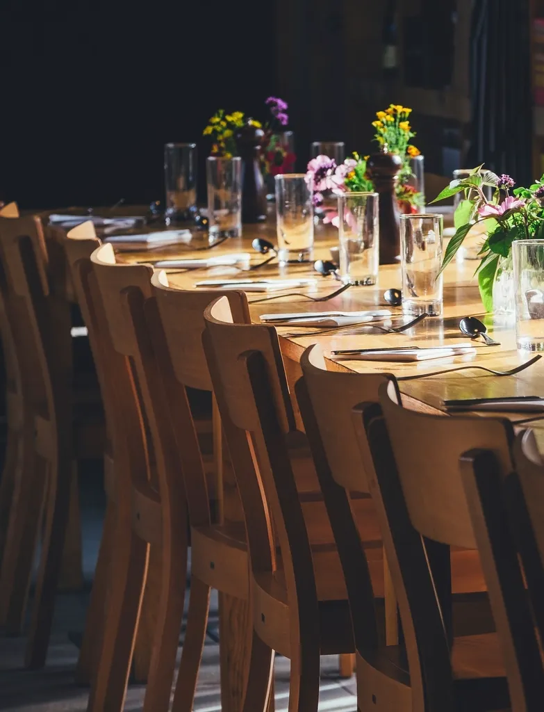 A long timber table set with candles and small floral arrangements in a dim reception room