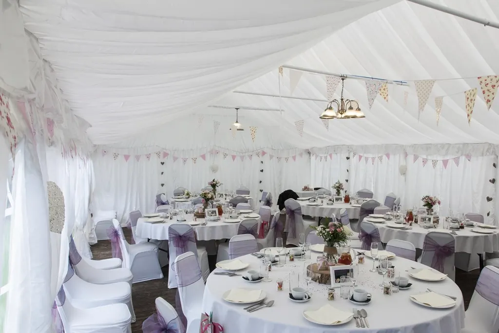 Round reception tables with covered chairs inside a white marquee
