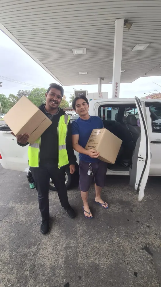 A customer and a seller with boxes of WakaWax next to a white ute